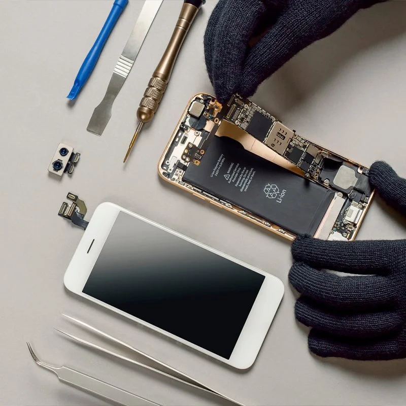 Técnico reparando un iPhone con herramientas de precisión sobre la mesa de trabajo